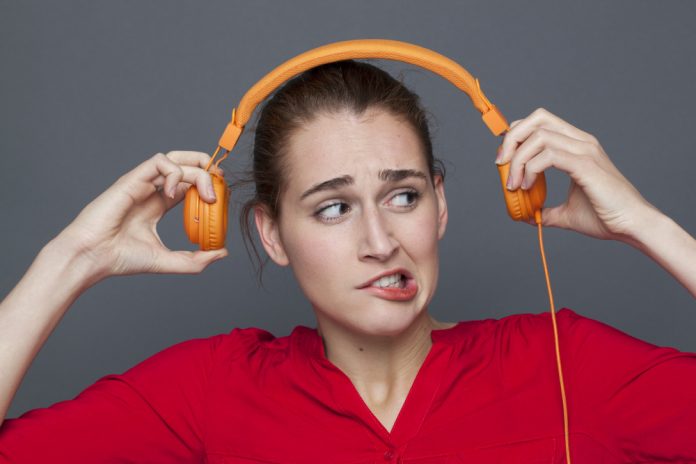 suspicious young woman grinding teeth for music pain or tinnitus