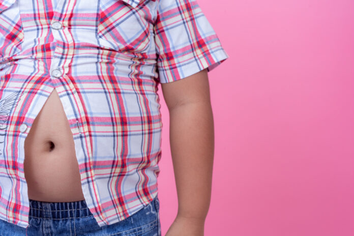 Obese boy who is overweight on a pink background.