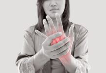Asian woman suffering from pain in bone against gray
