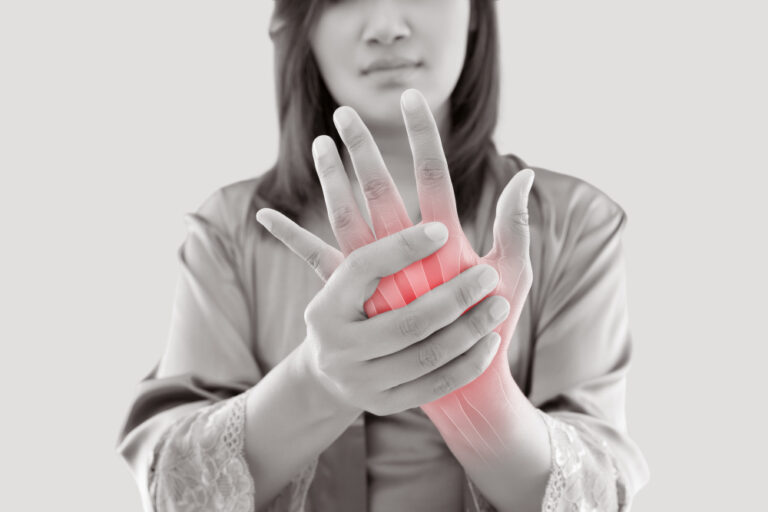 Asian woman suffering from pain in bone against gray